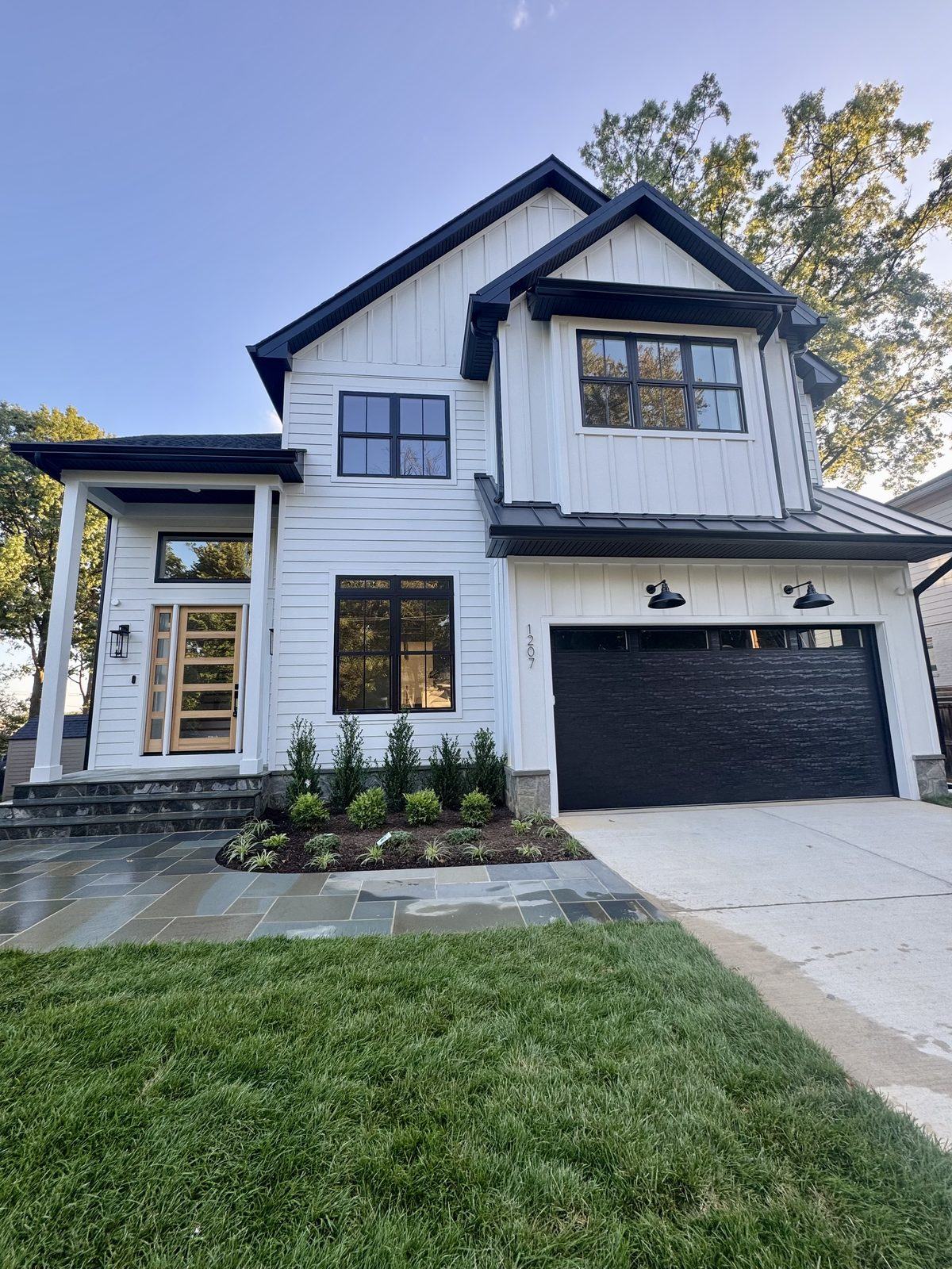 The rebuilt home, with white siding, a covered porch and new driveway